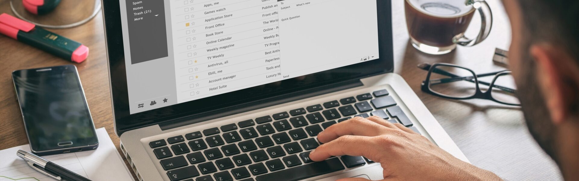 Emails list on a laptop screen, office background
