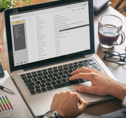 Emails list on a laptop screen, office background