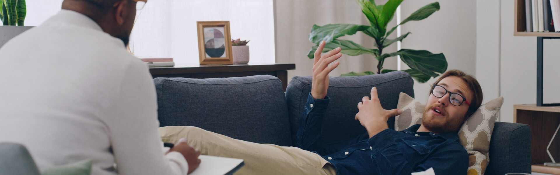Man on sofa consulting psychologist in therapy, healthcare clinic and medical office for mental hea