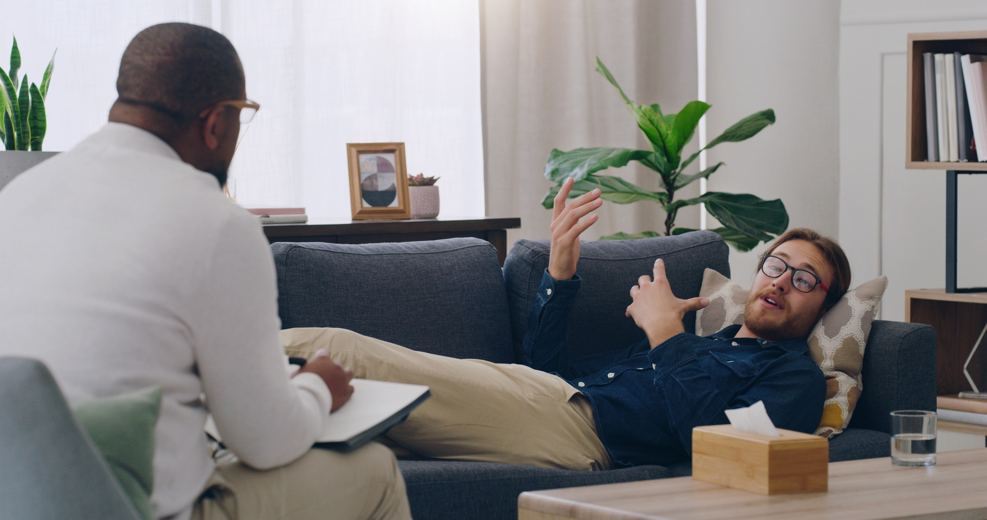 Man on sofa consulting psychologist in therapy, healthcare clinic and medical office for mental hea