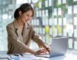 Young businesswoman typing an e-mail on laptop at home office.