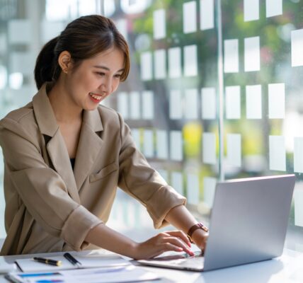 Young businesswoman typing an e-mail on laptop at home office.