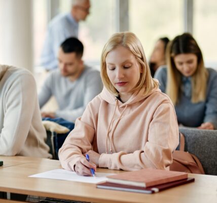 Young woman writing exam in lecture hall at the university.