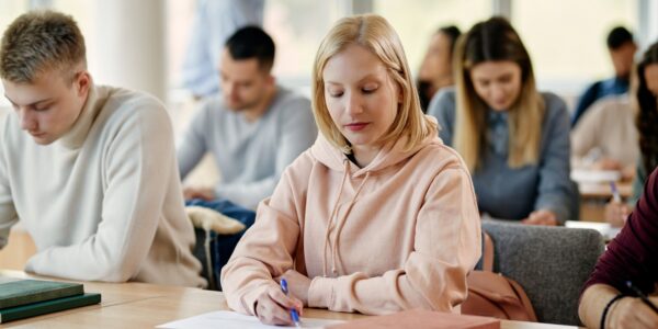 Young woman writing exam in lecture hall at the university.
